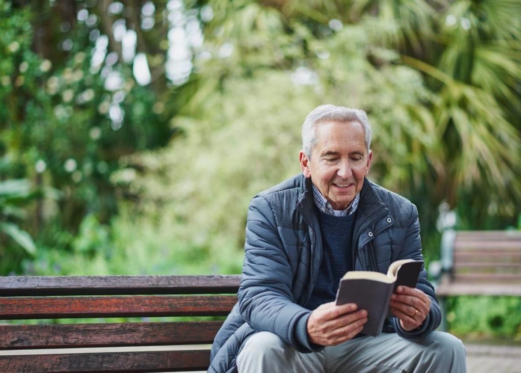 A senior man reading a book in the park