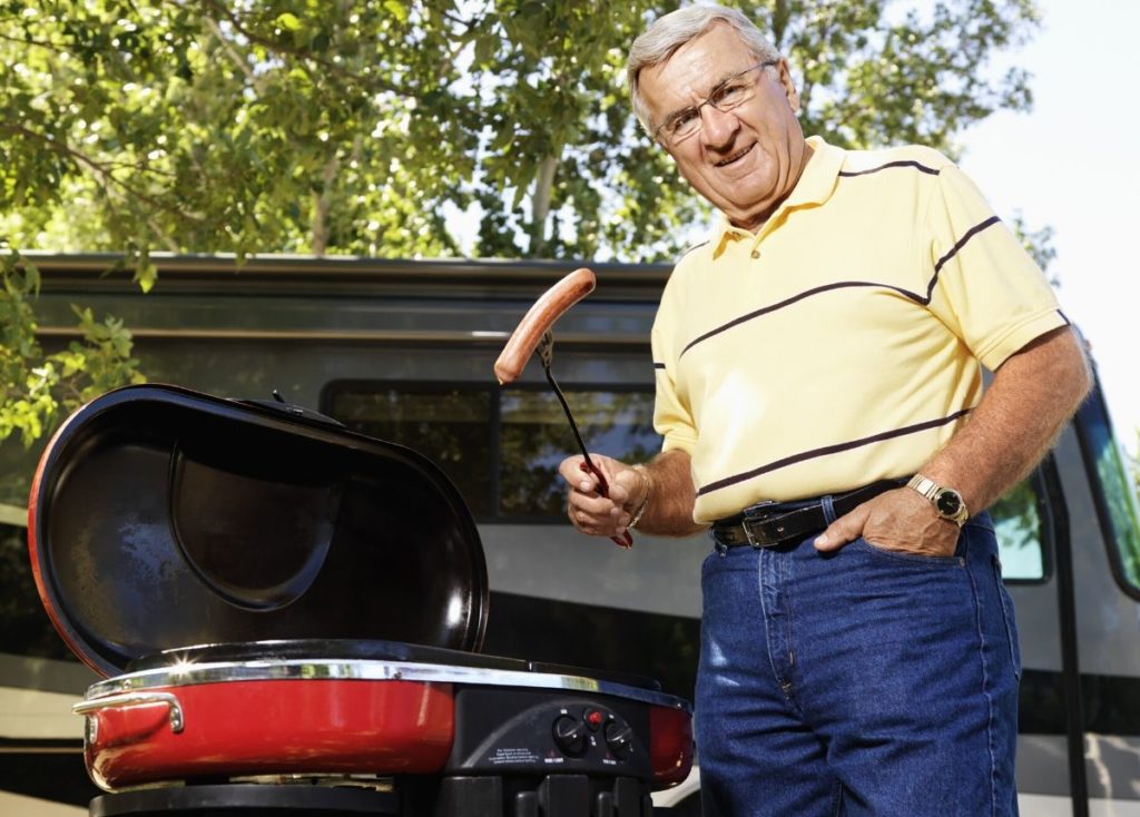 retired man grilling by RV